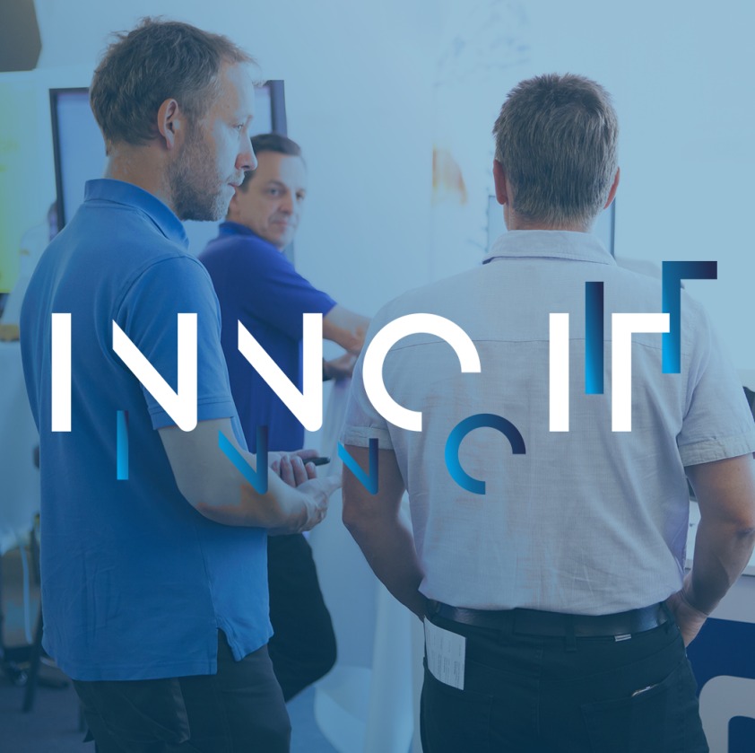 Drei Personen im fachlichen Austausch auf einer IT-Veranstaltung mit abstraktem INNO IT Schriftzug